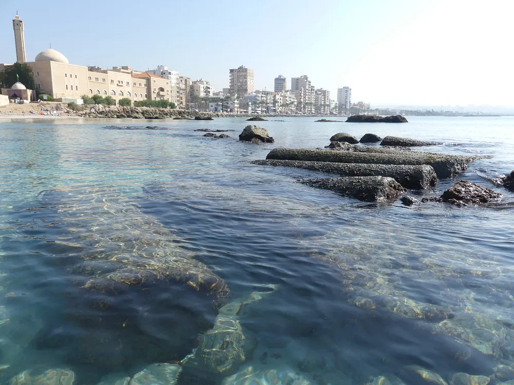 Ancient columns in the submerged Egyptian harbour of Tyre (Sour), southern Lebanon, with the modern city skyline behind, 4 November 2019.