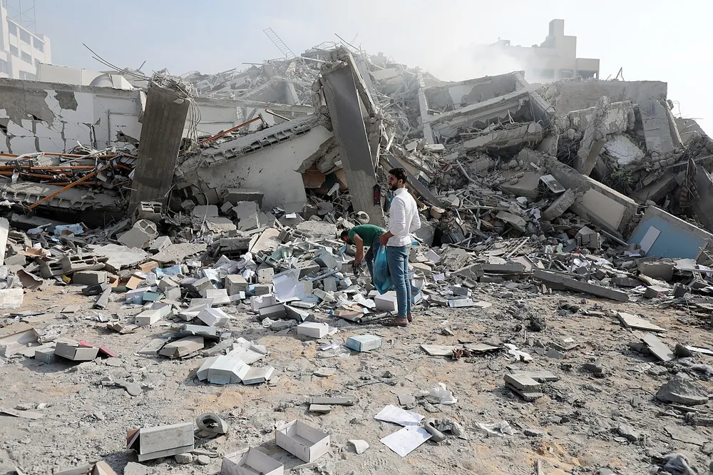 Palestinians inspect the ruins of Watan Tower in Gaza City after Israeli airstrikes, 8 October 2023.