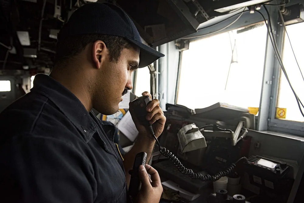 A sailor aboard the guided-missile cruiser USS San Jacinto (CG 56) communicates with an Iranian warship during a Strait of Hormuz transit, 21 July 2016.