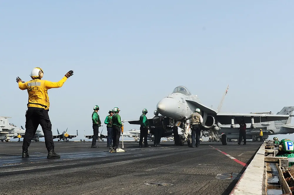 Flight-deck crew prepare an F/A-18 on USS George H.W. Bush (CVN-77) during flight operations. Photo: U.S. Navy, public domain.